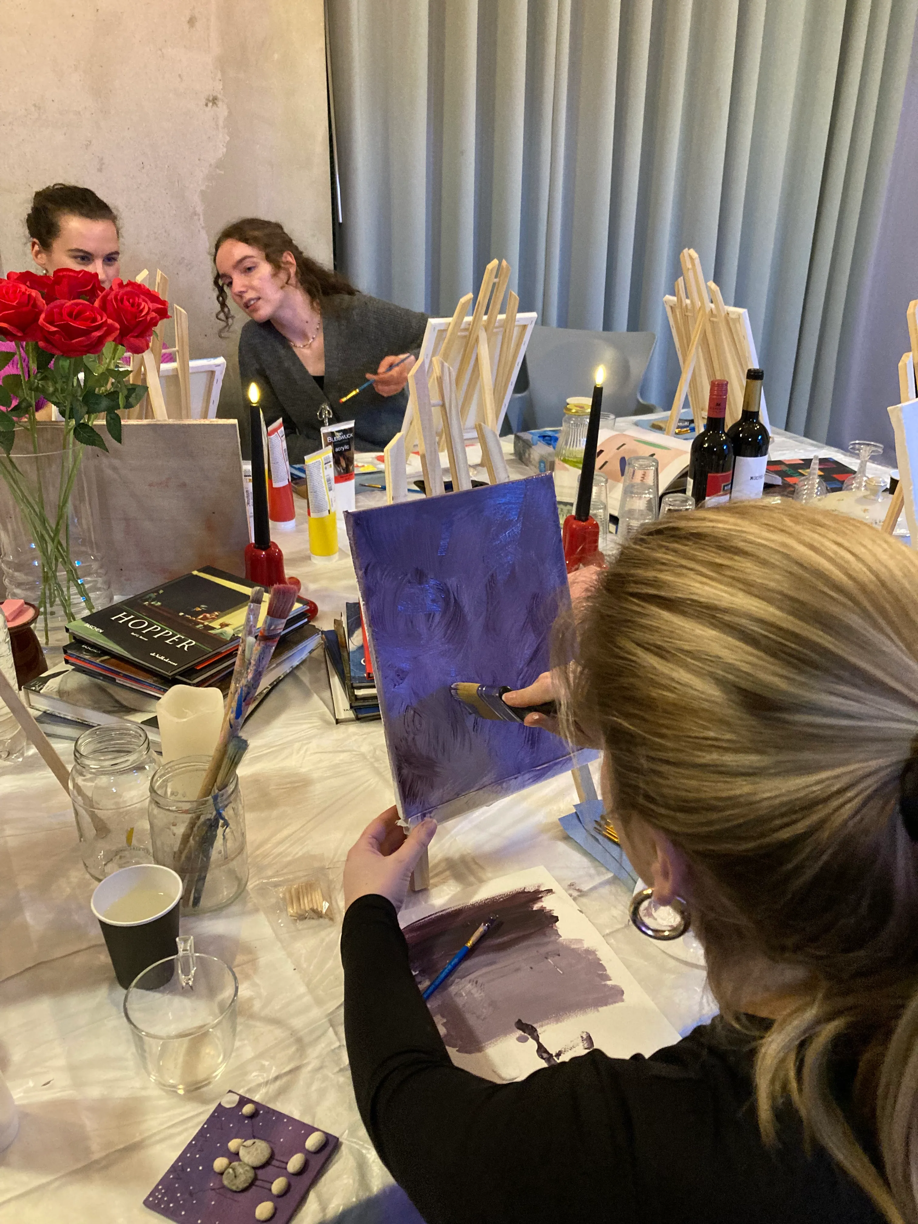 Deelnemers schilderen kleurrijke abstracte canvassen met een glas wijn erbij